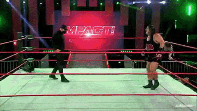 two wrestlers are standing in a wrestling ring with a sign that says impact