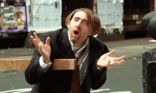 a man in a suit and tie is making a funny face with his hands outstretched .