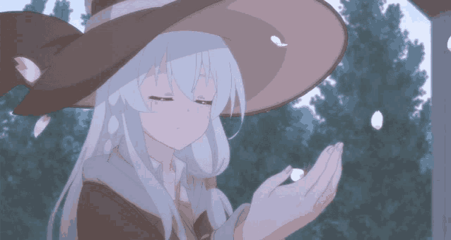 a girl with white hair wearing a witch hat is holding something in her hands