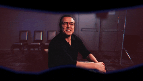 a man wearing glasses and a black shirt smiles for the camera