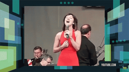 a woman in a red dress singing into a microphone in front of a youtube.com advertisement