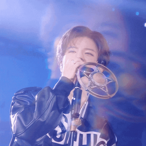 a woman singing into a microphone wearing a jacket that says spitz