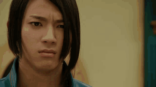 a close up of a young man with long hair making a face