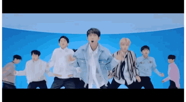 a group of young men are dancing in front of a blue background in a room .