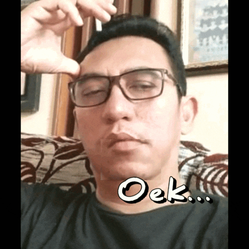 a man wearing glasses is sitting on a couch with the word oek on his face