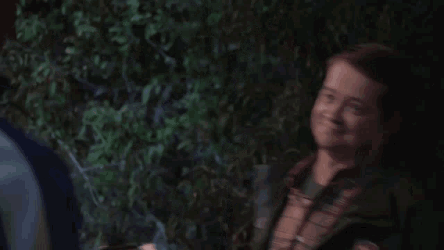 a man in a plaid shirt is smiling and wearing a jacket with a patch on it that says ' uc '