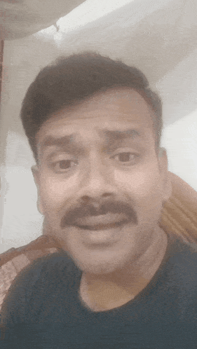 a man with a mustache looks at the camera with a surprised look on his face