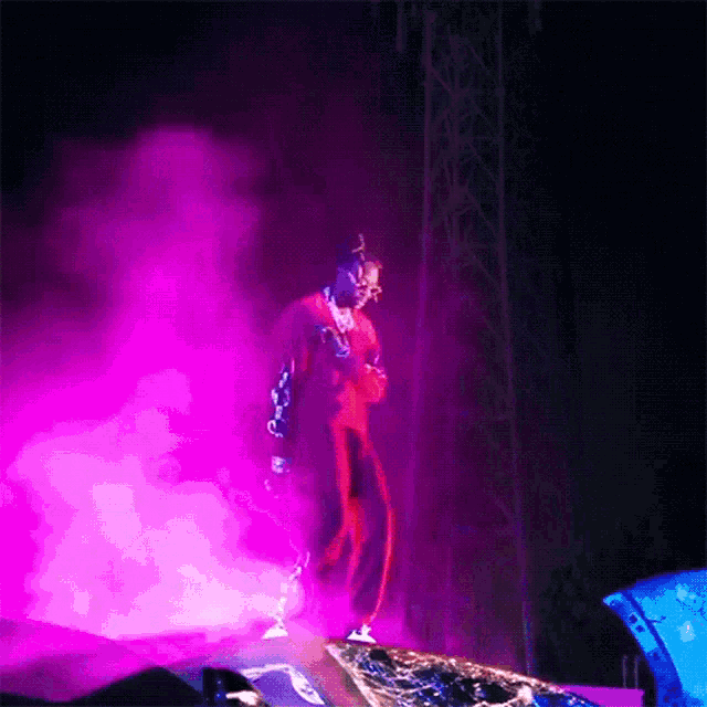a man singing into a microphone on a stage with purple lights behind him