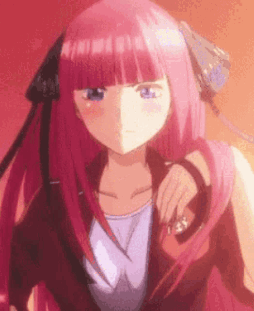 a girl with pink hair and blue eyes is standing in front of a red wall .