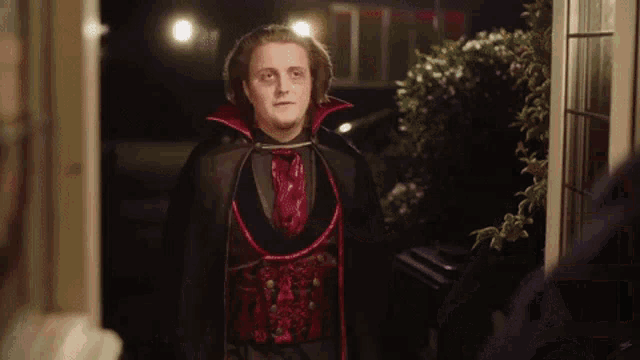 a man in a vampire costume stands in front of a door