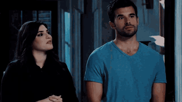 a man in a blue shirt is standing next to a woman in a black shirt