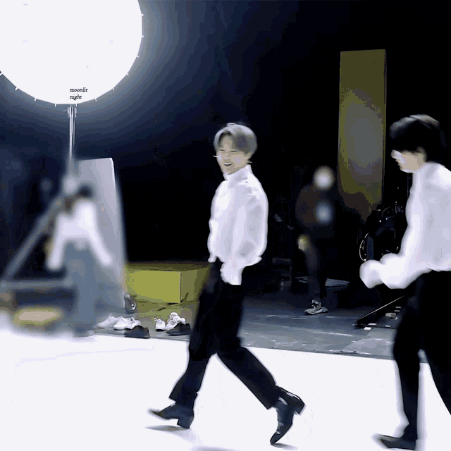 a man in a white shirt is walking in front of a light which says ' panasonic ' on it