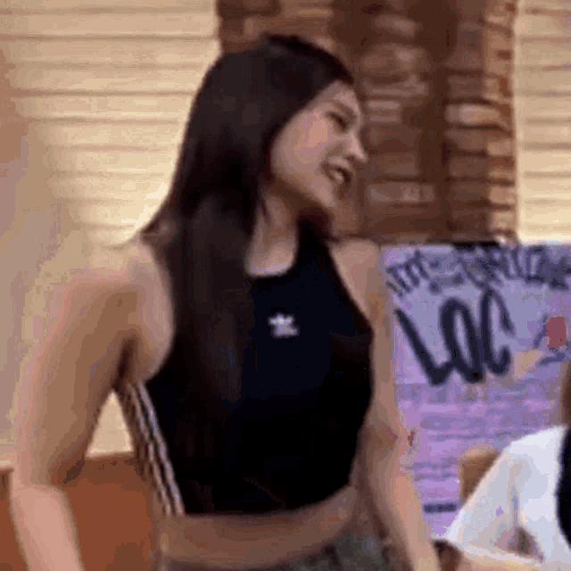 a woman in a black crop top is standing in front of a window and smiling .