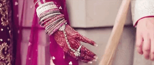 a bride and groom are holding hands on their wedding day and the bride is wearing a ring on her finger .