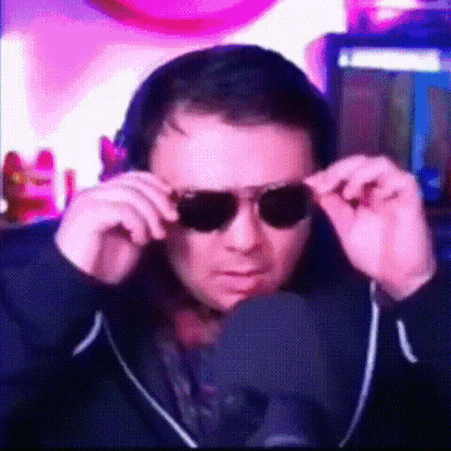 a man wearing headphones and sunglasses is looking at the camera .