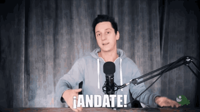 a man stands in front of a microphone with the words andate written on the bottom
