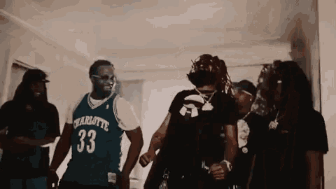 a group of men are standing in a room and one of them is wearing a charlotte jersey .