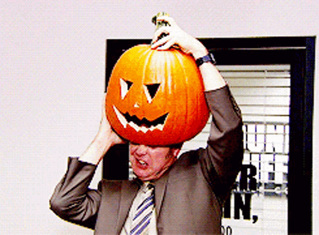 a man in a suit and tie is holding a pumpkin over his head