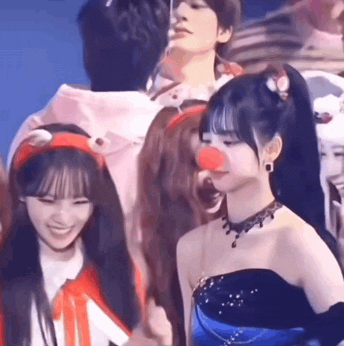 a group of young women are standing next to each other and one of them has a red nose .
