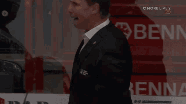 a man in a suit and tie stands in front of a sign that says benn