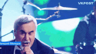 a man in a tuxedo singing into a microphone with vkfest in the upper right corner