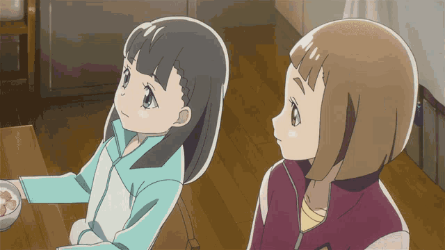 two anime girls are sitting at a table with a bowl of food
