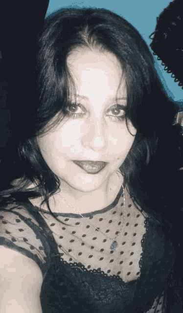 a woman with dark hair is wearing a black polka dot shirt