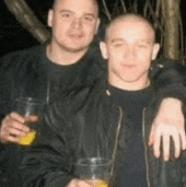 two men standing next to each other holding drinks