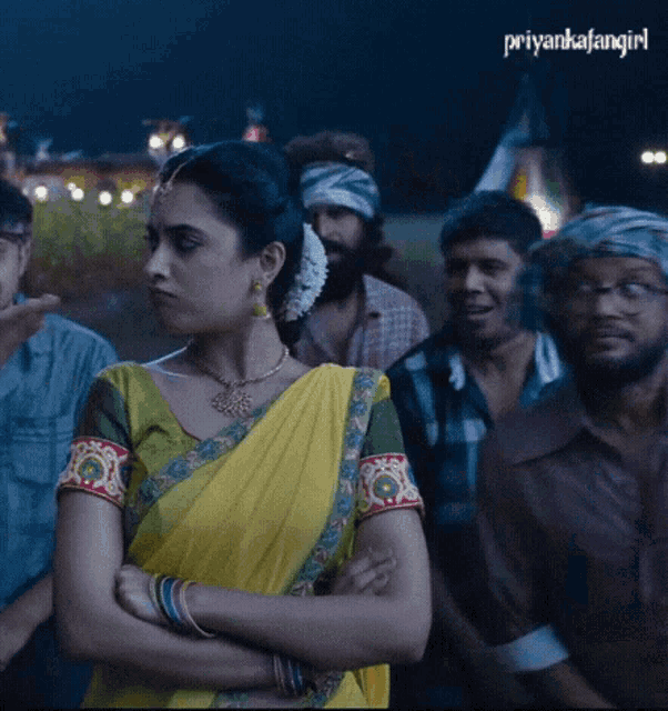 a woman in a yellow sari stands in a crowd of people