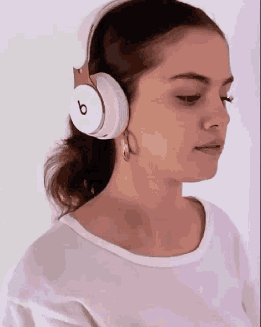 a woman wearing a pair of white beats headphones .
