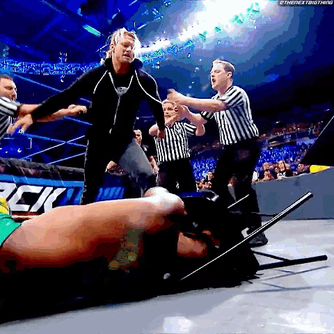 a man is laying on the ground in a wrestling ring with a referee