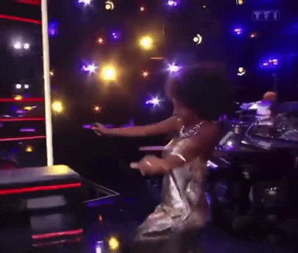 a woman in a silver dress is dancing in a dark room with a lot of lights .