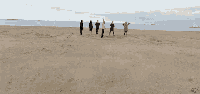 a group of people standing on a beach with a heart drawn in the sand that says i love you