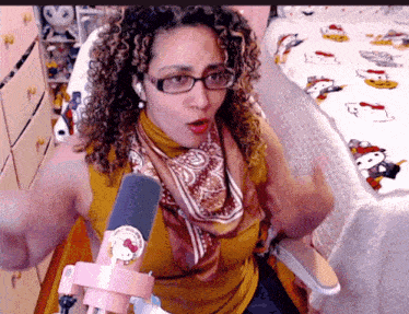 a woman wearing glasses and a hello kitty scarf is sitting in front of a microphone