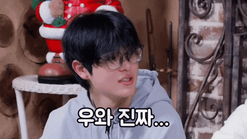 a man wearing glasses and a hoodie says something in a foreign language