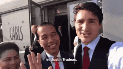 a man in a suit and tie is taking a selfie with a woman and another man .