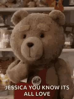 a teddy bear is wearing a red apron and holding a red bag .