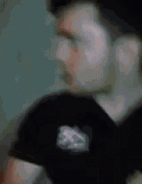 a blurry picture of a man wearing a black t-shirt with a mountain on it