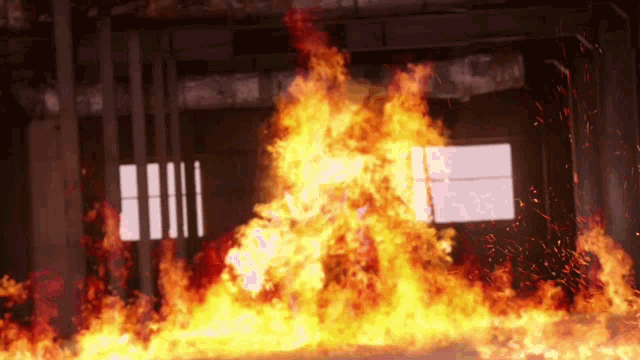 a large fire is coming out of a window in a dark room