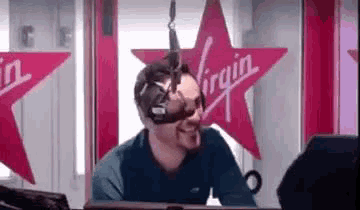 a man wearing headphones is sitting in front of a virgin logo .