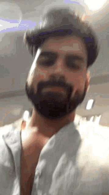 a man with a beard and a hat is making a face .