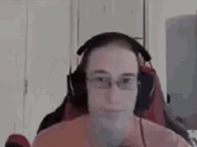 a man wearing headphones and glasses is sitting in a chair in front of a computer screen .