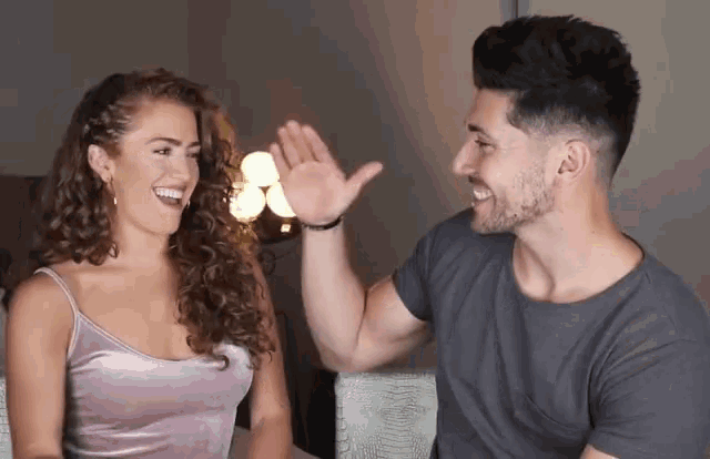 a man and a woman are giving each other a high five and smiling