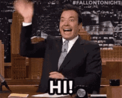 a man in a suit and tie is waving his hand and saying hi