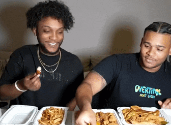 a man wearing an overtime shirt is eating a chicken wing