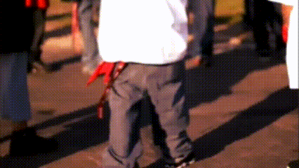 a man wearing a white shirt and grey pants is walking down the street