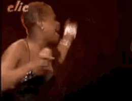 a woman in a black dress is singing into a microphone in front of a red curtain .