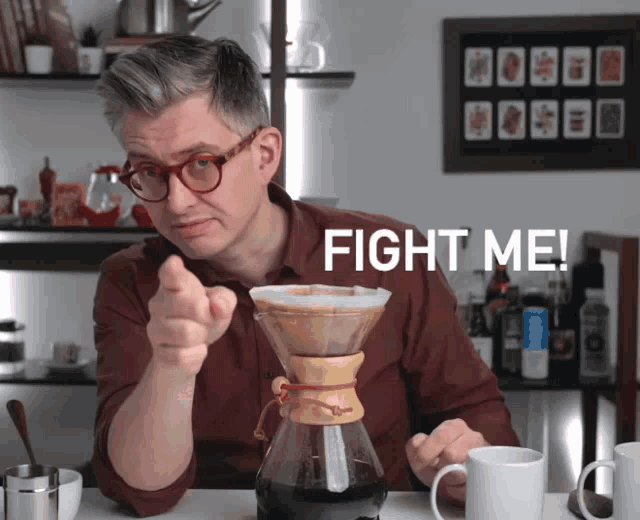 a man is pointing at a coffee maker with the words fight me behind him