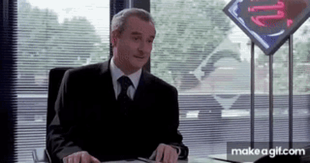 a man in a suit and tie is sitting at a desk in an office .