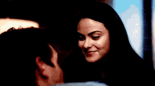 a man and a woman are hugging each other in a dark room and the woman is smiling .